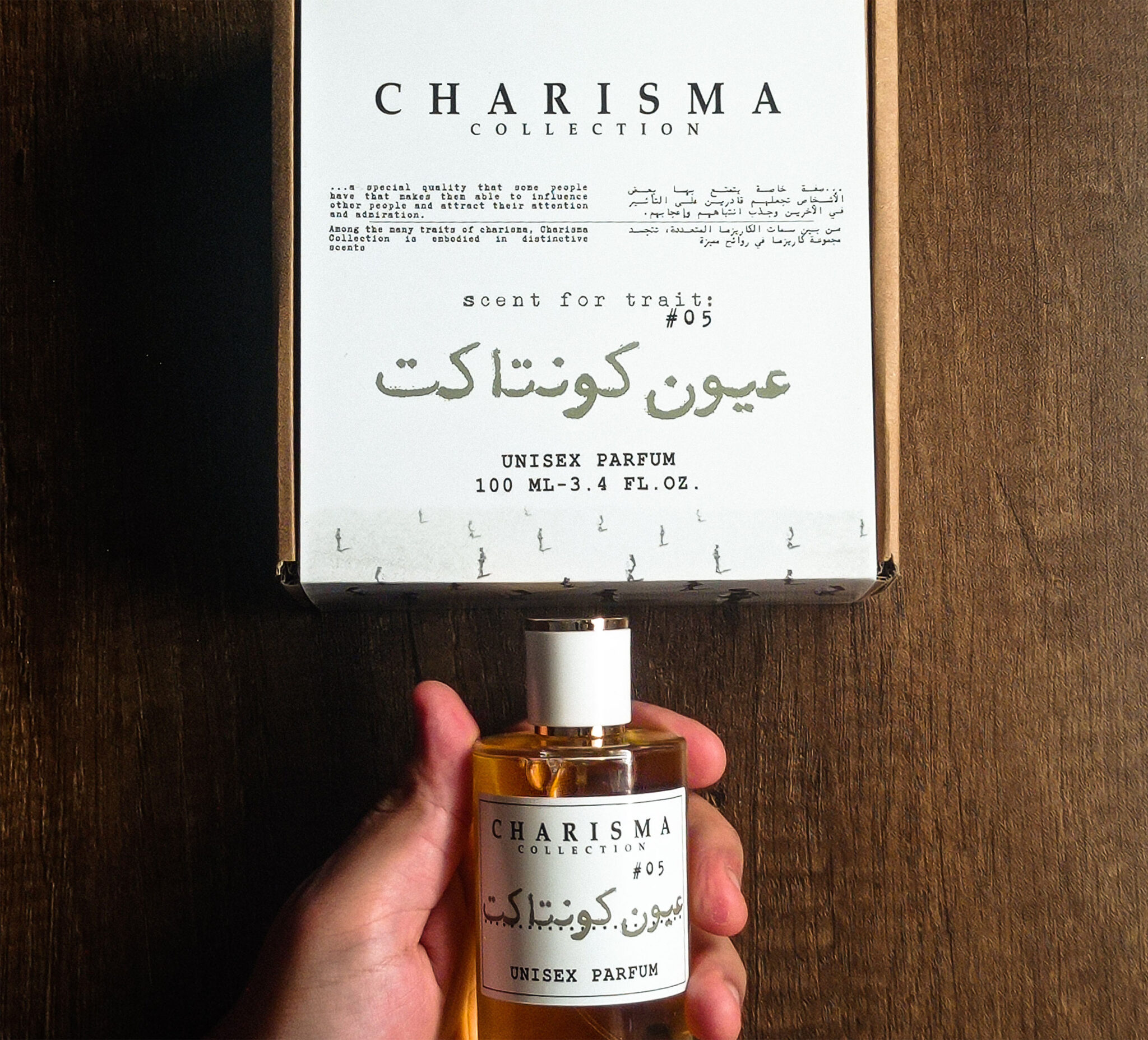 Charisma Collection unisex perfume Ouyon Contact fragrance bottles Held by hand on wooden brown background minimalist luxury branding Black and White large cropped